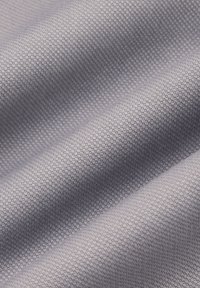 Teksturowana tkanina w jasnoszarym kolorze, z plecionym wzorem i subtelnie wypukłymi powierzchniami, ukazująca drobne detale i głębię.