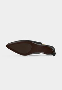 Chaussure à talon haut en cuir noir à bout pointu, vue par le dessous avec une semelle lisse et foncée et un petit talon courbé.