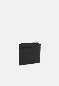 Schwarze gesteppte Brieftasche aus synthetischem Material. Verfügt über ein Zickzackmuster, einen Reißverschluss oben und mehrere Kartenfächer zur Organisation.