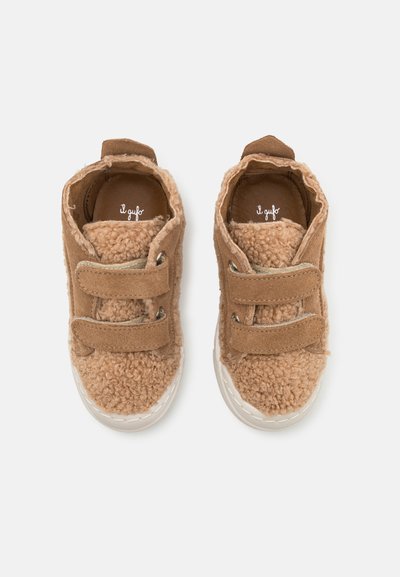 Brown toddler shoes with a soft, fluffy texture, featuring two Velcro straps, suede accents, and a white rubber sole.