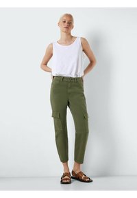 Maslinasto zelene cargo hlače imaju slim fit kroj, bočne džepove i tkaninu od mješavine pamuka, upotpunjene bijelim majicom na bretele i smeškim sandalama.