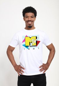 White cotton t-shirt featuring a colorful MTV logo in yellow and pink, along with "MUSIC TELEVISION" and "1981" in black.