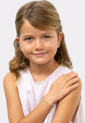 Ein Armband aus Gold und Pastellperlen, das am Handgelenk eines Kindes getragen wird. Das Kind hat hellbraune Haare und ein weiches, pinkfarbenes ärmelloses Oberteil.