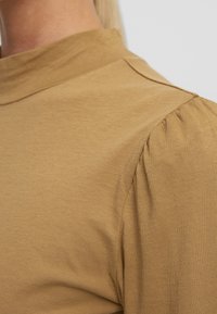 Khaki kolorowa bluzka wykonana z gładkiego materiału bawełnianego, z wysokim kołnierzem i bufkami dla dodatkowej tekstury i detalu.