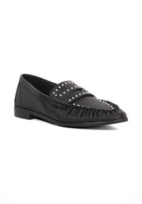 Black leather loafers with a fringed design, studded accents on the vamp, and a low, flat heel. Smooth texture and pointed toe.