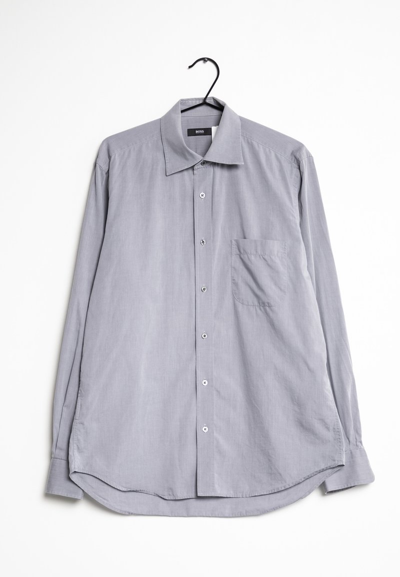 Camicia grigia chiaro a maniche lunghe con colletto a punta, chiusura con bottoni, una singola tasca sul petto e orlo curvo. Realizzata in un tessuto liscio.
