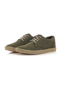 Zapatos de lona verdes con suela beige y acentos de yute trenzado. Presentan un detalle de talón de cuero marrón y cordones claros.
