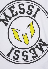 Hvit T-skjorte med et sirkulært design og fet svart tekst som leser "MESSI" og gule detaljer i sentrum formet som en stilisert logo.