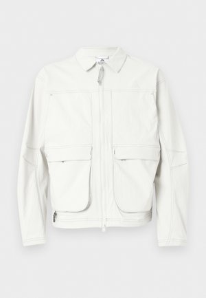 Weiße Jacke mit Frontreißverschluss, zwei großen Klappentaschen, langen Ärmeln und spitzem Kragen, vor einfarbigem Hintergrund gezeigt.