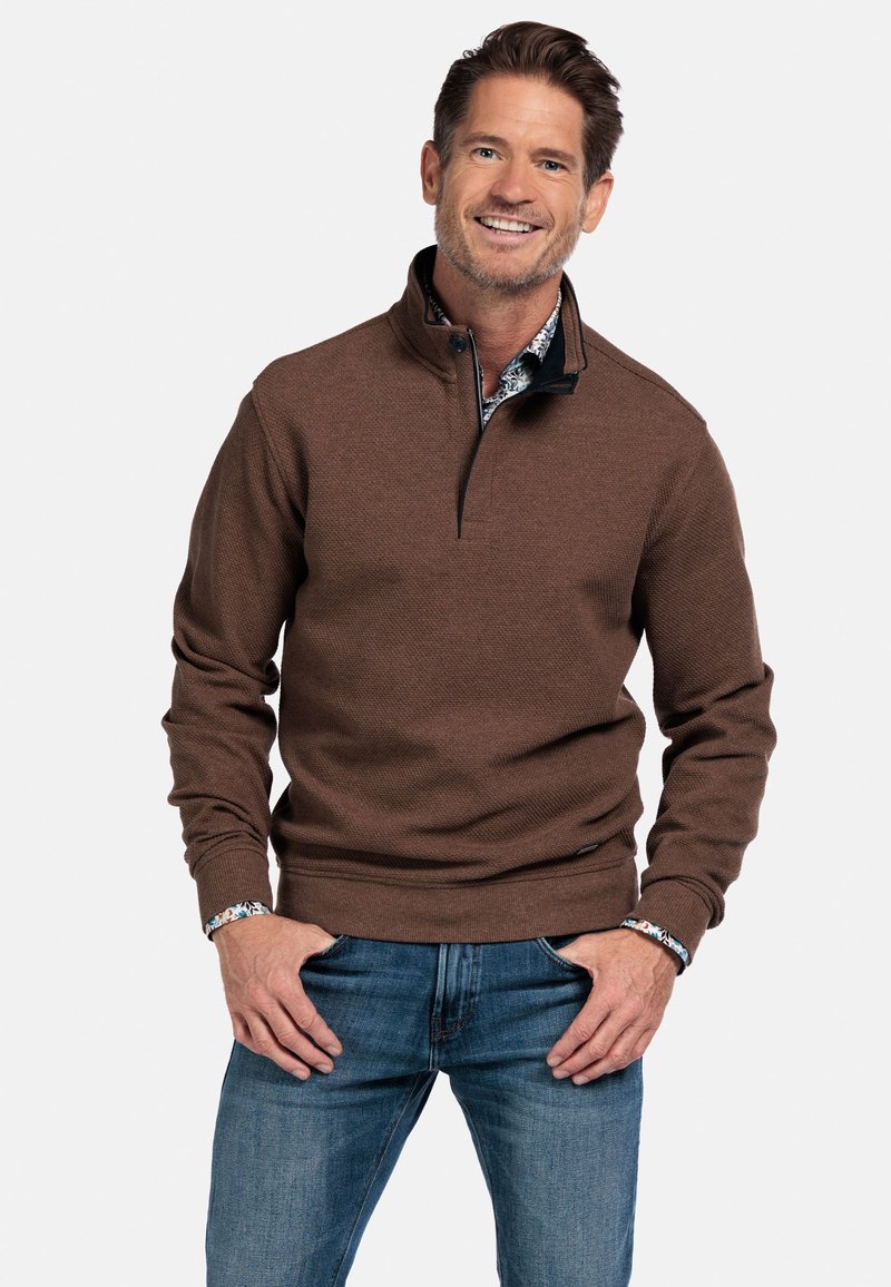 Bruine pullover met een gestructureerde weving en een kwart rits, voorzien van een zwarte kraag en gelaagd met een gestreept shirt eronder.