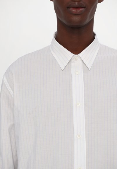 Chemise blanche avec de fines rayures verticales bleues, fermeture à boutons sur le devant et un col classique. Tissu léger avec une texture lisse.