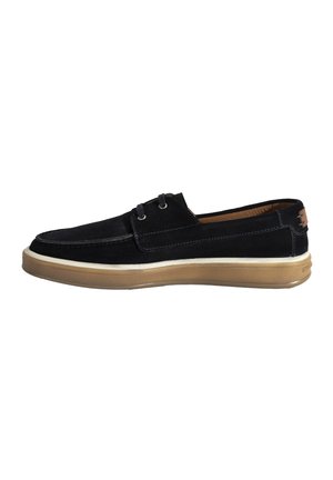 Schwarze Wildleder-Slipper mit einer beigefarbenen Gummisohle, ausgestattet mit zwei Ösen für Schnürsenkel und einem hellbraunen Akzent auf der Rückseite.