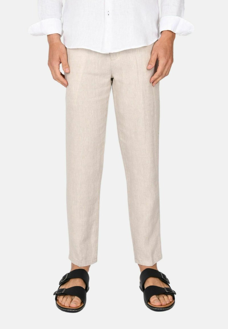 Pantaloni in lino beige con vestibilità su misura, caratterizzati da una texture liscia e una lunghezza cropped, abbinati a sandali neri.