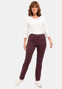 Bordeauxkleurige broek van een katoenmix met een slim fit en vijf zakken, gecombineerd met een witte top met driekwart mouwen en witte sneakers.