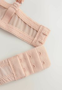 Nastaviteľný béžový ramienok podprsenky s tromi zapínacími háčikmi a očkami a jemným prešitím na svetlom pozadí.