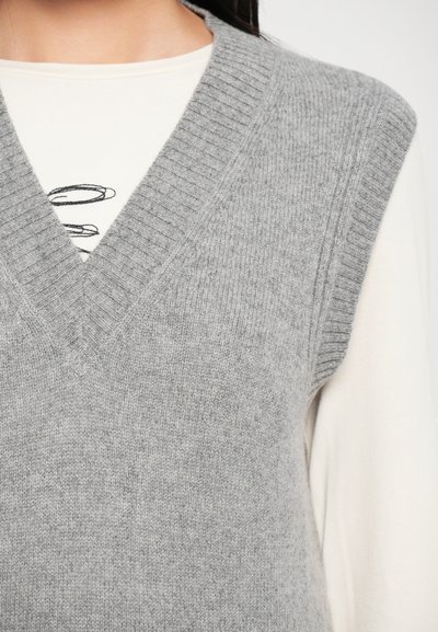 Gray knitted vest with a deep V-neck and ribbed trim, layered over a cream long-sleeve top, showcasing a soft texture and casual design.