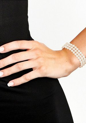 Bracelet en perles blanches avec plusieurs brins, perles rondes lisses, porté sur une main au fini naturel avec un fond noir.