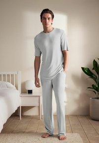 Lys grå, kortærmet pyjamas sæt lavet af blødt stof; afslappet pasform med lige bukser; glat tekstur, ingen synlige mønstre eller detaljer.