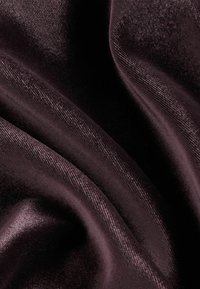 Dunkelviolettes Samtgewebe mit einer glatten Textur, das weiche Falten und einen subtilen Glanz aufweist und ein reichhaltiges, luxuriöses Erscheinungsbild präsentiert.