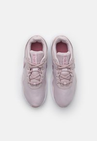 Scarpe da ginnastica rosa chiaro con tomaia in tessuto liscio, dettagli testurizzati e suole in gomma bianca. Presentano una chiusura con lacci e un colletto imbottito.