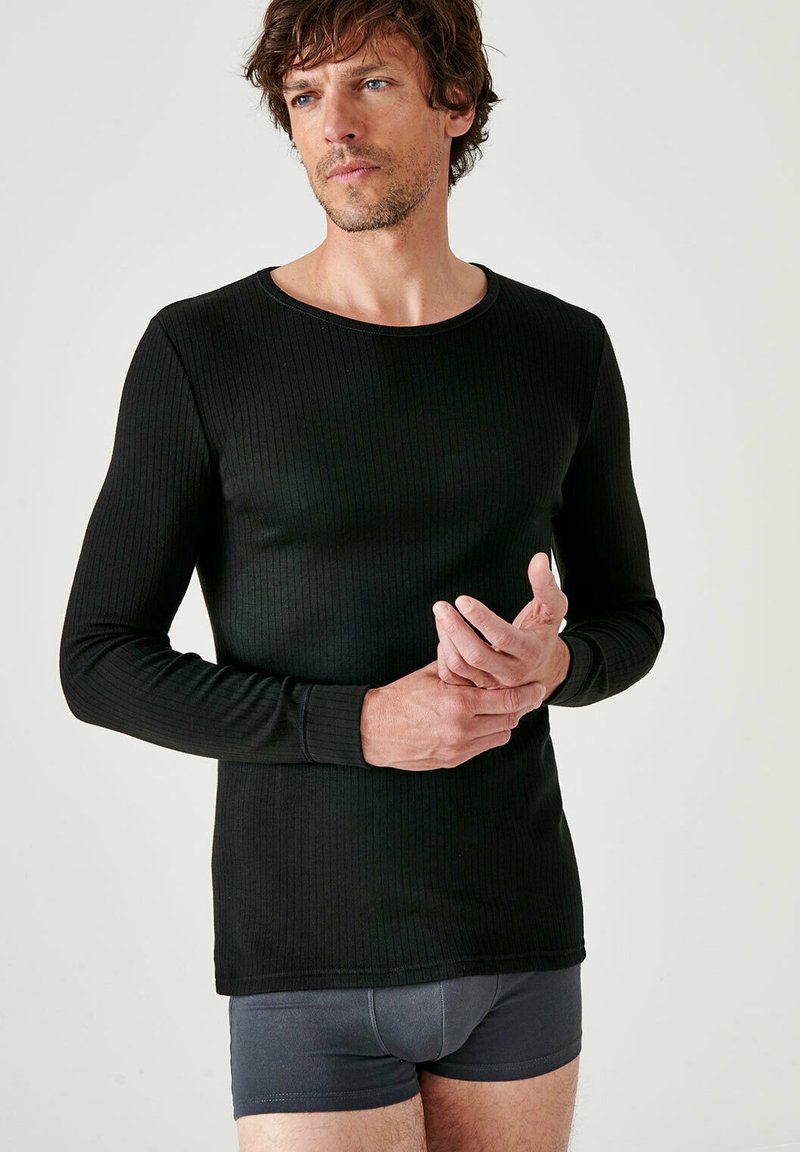 Zwarte langslacem shirt met een geribbelde textuur en een ronde halslijn, gecombineerd met grijze boxer shorts. Gladde stof met een aansluitend ontwerp.