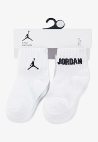 Chaussettes blanches montantes, légères, avec le texte et le logo "JORDAN" en noir. Lot de six. Texture lisse, forme standard de chaussette.