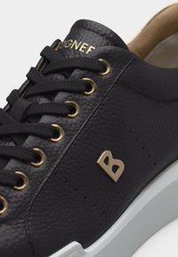 Μαύρο δερμάτινο αθλητικό παπούτσι με χρυσά οιλέτ, μαύρα κορδόνια, χρυσό λογότυπο "B" στο πλάι και λευκή σόλα.