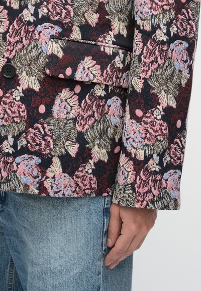 Σακάκι με λουλουδάτο σχέδιο και πολύχρωμα λουλούδια σε σκούρο φόντο, με ένα κουμπί, κομψό πέτο και υφασμάτινη υφή.