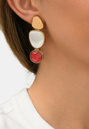Boucles d'oreilles dorées présentant trois formes géométriques : un haut texturé en or, un milieu iridescent blanc et un élément circulaire rouge en bas.