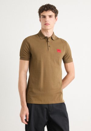 Brown polo shirt with short sleeves, ribbed cuffs, three-button placket, and a red branded patch on the left chest.