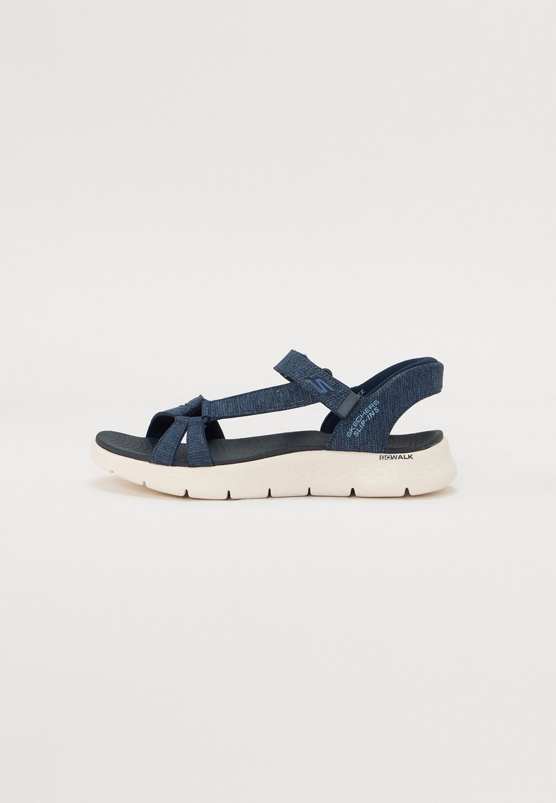 Mørkeblå sandal med tekstilremmer og en myk sort fotseng. Har en lysfarget, polstret såle for komfort og støtte.