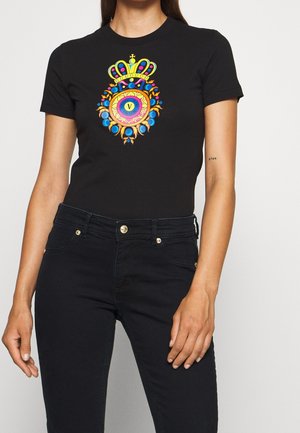 Camiseta negra de manga corta con un diseño gráfico colorido que muestra una corona, patrones circulares y acentos vibrantes en la parte delantera.