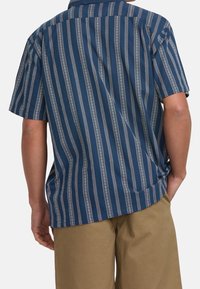 Short-sleeve shirt in dark blue with vertical white stripes and a subtle geometric pattern. Relaxed fit with a pointed collar and button placket.