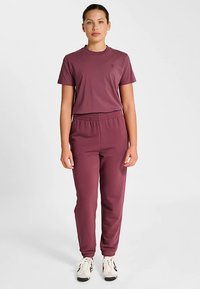 Vinrødt sportssæt med en t-shirt med korte ærmer og joggers med elastisk talje. Glat stof, tætsiddende design og smalle bukser.