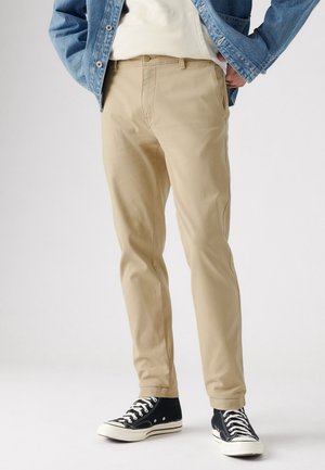 Beige chinos van katoen, met een rechte pijpdesign, zijzakken, en gecombineerd met zwarte hoge sneakers.