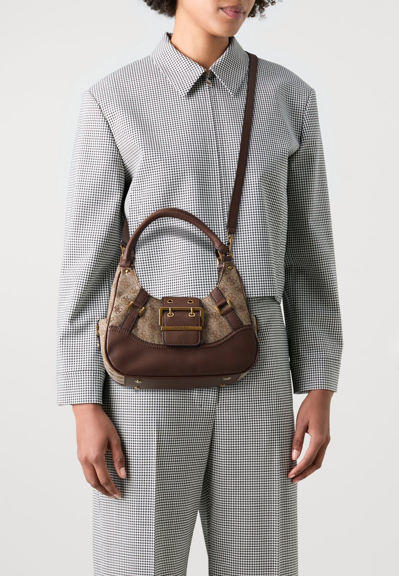 Bolsa de pele castanha e tecido estampado com uma silhueta curva, ferragens douradas e uma alça de ombro destacável. Exibida num modelo.