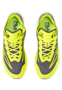 Zapatillas de correr grises con detalles en amarillo neón, que presentan una parte superior texturizada, cordones prominentes y un diseño elegante. Diseñadas para el rendimiento y la comodidad.