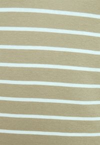 Beżowy materiał w białe poziome paski. Gładka tekstura, średniej wagi dzianina, jednolity wzór na całej powierzchni.