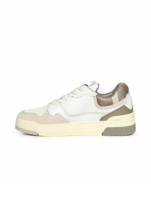 Zapatilla baja en blanco y beige con cordones delanteros, cuello acolchado y suela de goma texturizada, mostrada de lado sobre un fondo blanco.