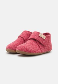 Červené filcové de slippers s suchým zipsom, mäkkou textúrou, okrúhlym tvarom špičky a béžovou gumovou podrážkou. Viditeľná značka Kitzbühel.