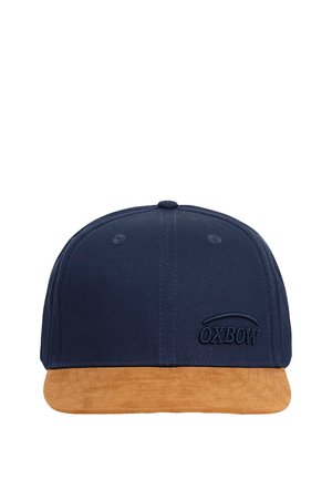 Casquette bleu marine avec une visière en suède beige. Présente un logo brodé "OXBOW" en bleu marine. Design structuré avec des œillets de ventilation.