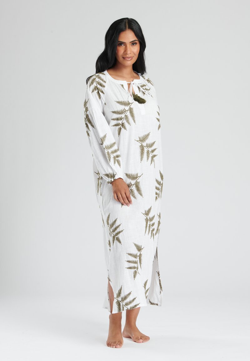 Vit långärmad klänning med grön ormbunksprint, med sidokilar och en snörning vid halsringningen i ett lättviktigt tyg.