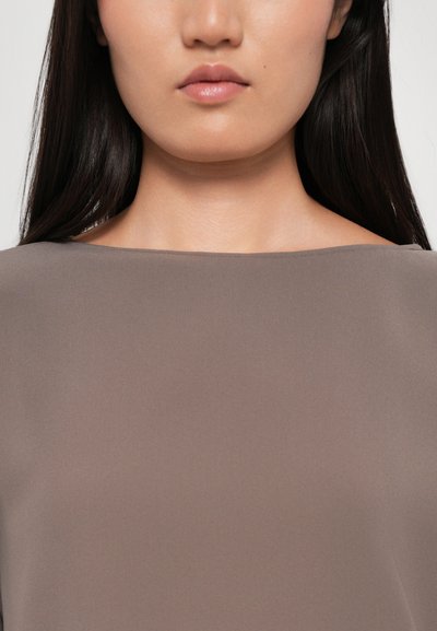 Taupe blouse with a smooth, matte fabric, featuring a wide, rounded neckline and short sleeves, highlighting a simple silhouette.
