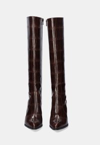 Botas de cuero marrón de altura hasta la rodilla, con punta afilada y un acabado brillante con textura de piel de cocodrilo. Suela plana con una forma distintiva.