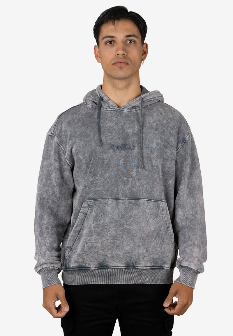 Sudadera con capucha gris hecha de tela suave, con un acabado texturizado, cordones y un bolsillo delantero. Marca sutil en hilo oscuro en el pecho.