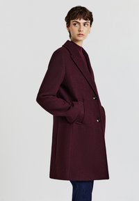 Burgundy wool coat with a notched collar, double-button closure, side pockets, and a relaxed silhouette. Smooth texture and tailored design.