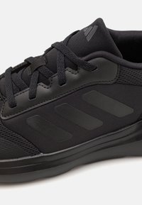 Czarne buty sportowe wykonane z siateczki i materiałów syntetycznych, z teksturowanym czarnym noskiem, widocznym logo z trzema paskami oraz sznurowanym fasonem.