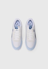 Sneakers bianchi con accenti azzurri, tessuto textured, colli imbottiti e una soletta decorata con palme. Logo Puma visibile.
