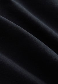 Mørk marineblåt stof med en glat struktur, der har bløde bølger og en let glans, hvilket skaber dybde og visuelt interesse.