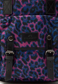 Zaino con motivo leopardato nero, blu e rosa; presenta dettagli in pelle nera; dotato di spallacci regolabili e una patch del logo.